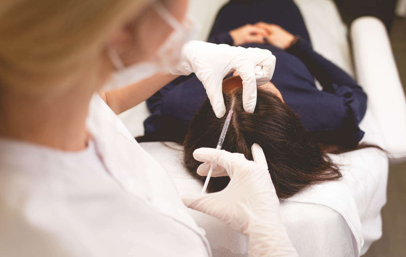 A dermatologist gives an injection to a woman with hair loss. Concept of hair loss treatments, surgery, injections, cost.